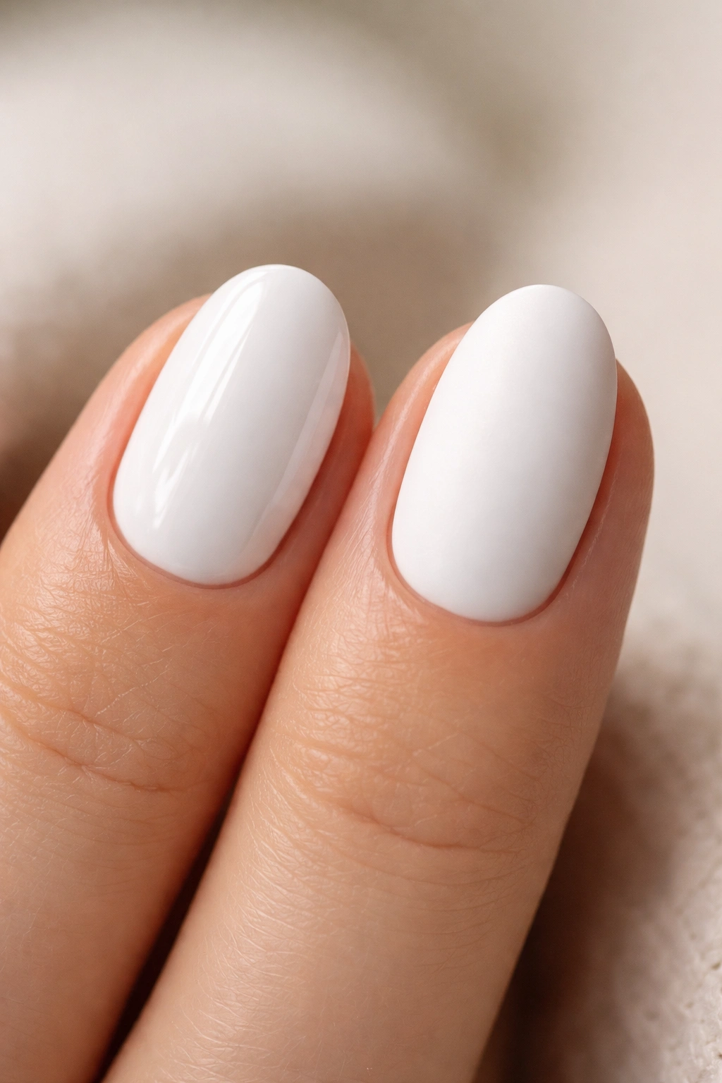 Close-up of two white short oval nails showing glossy and matte finishes
