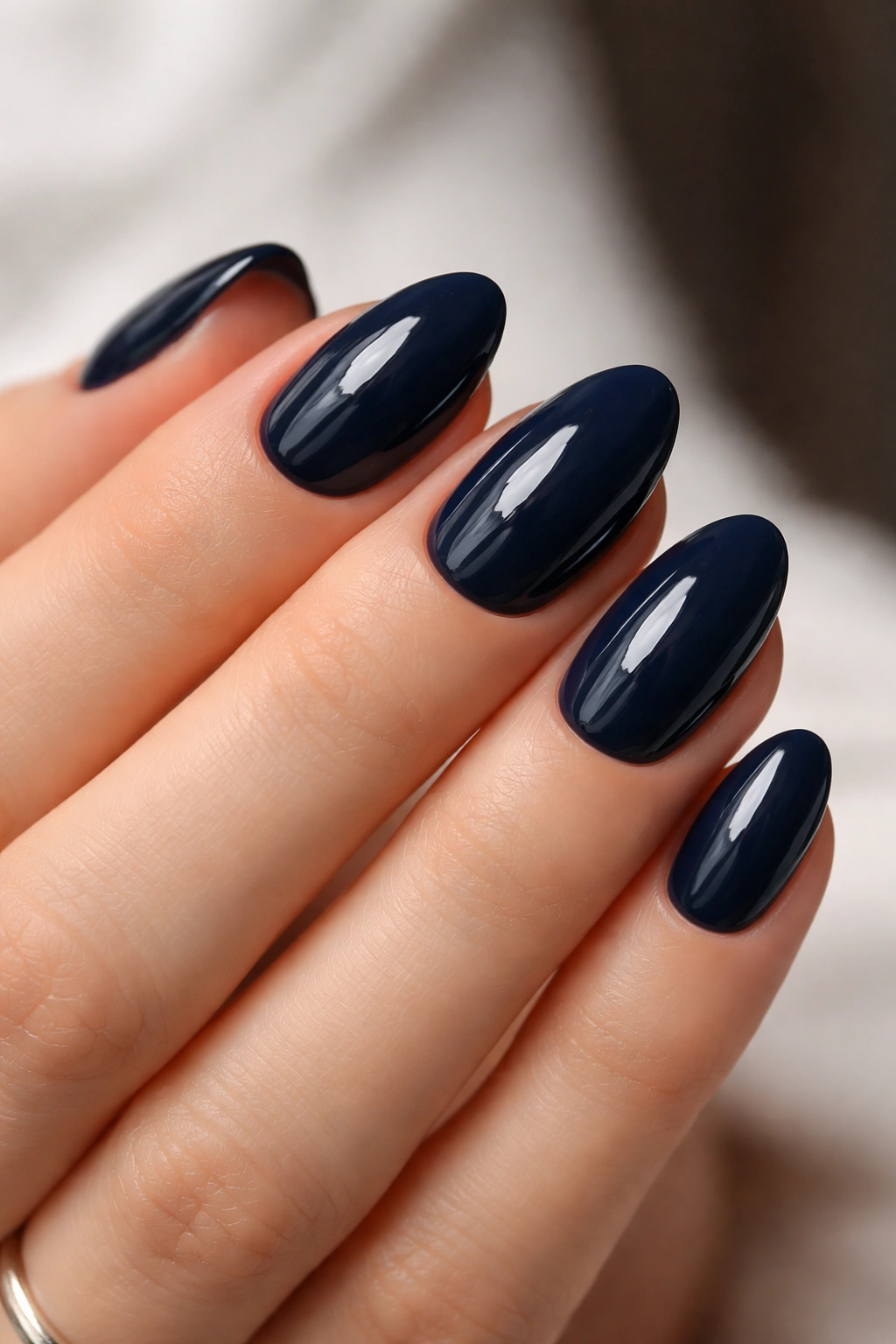 Close-up of glossy navy almond nails with a high-shine finish
