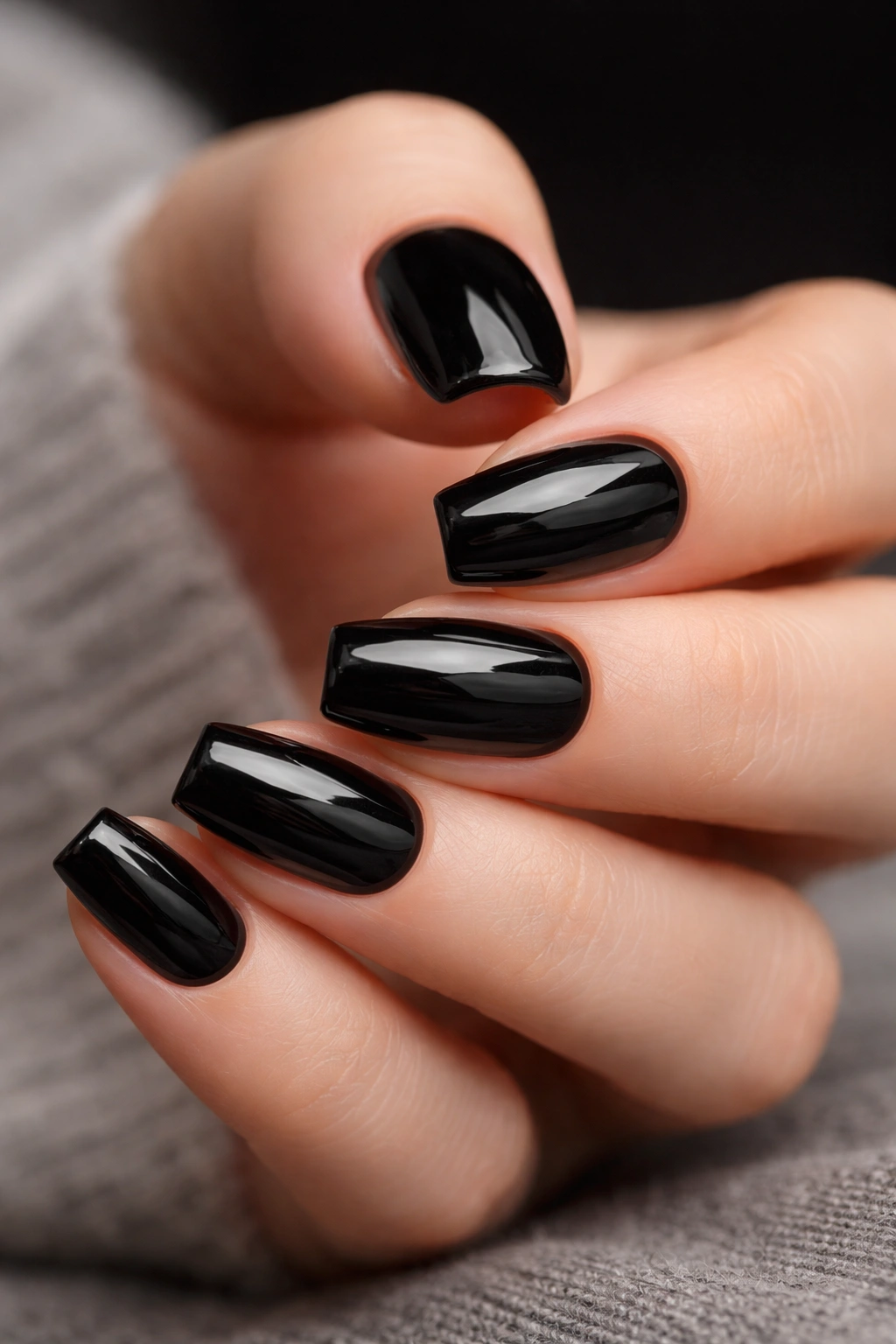 Close-up of glossy piano-black short ballerina nails with reflective surface