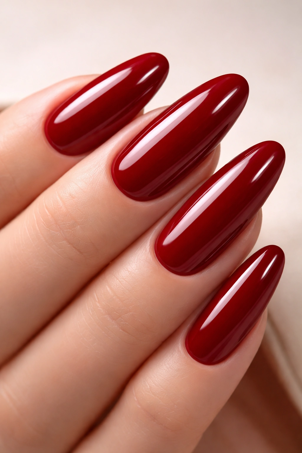Close-up of long round nails with glossy deep red polish and sharp edges