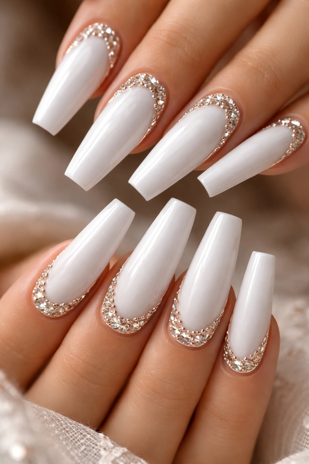 Close-up of glossy white coffin nails with rhinestones along the edge