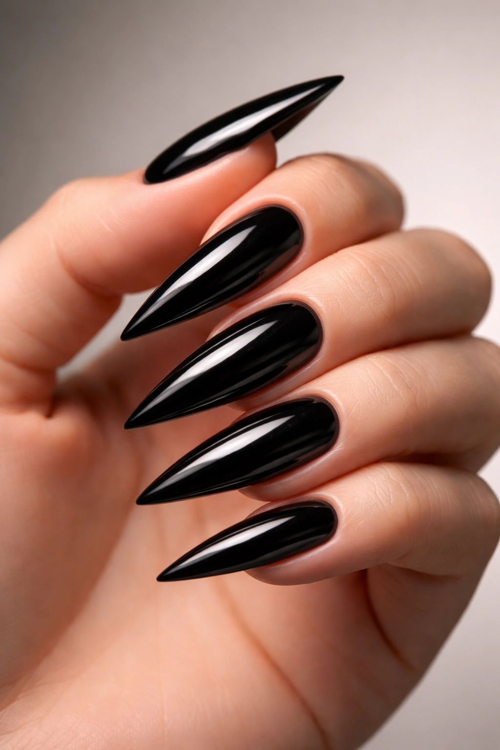 Glossy black stiletto nails with mirror finish on a hand