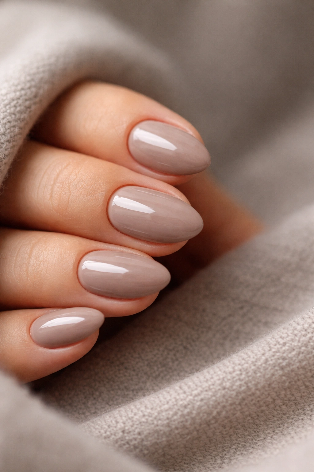 Close-up of glossy taupe almond nails on a short shape