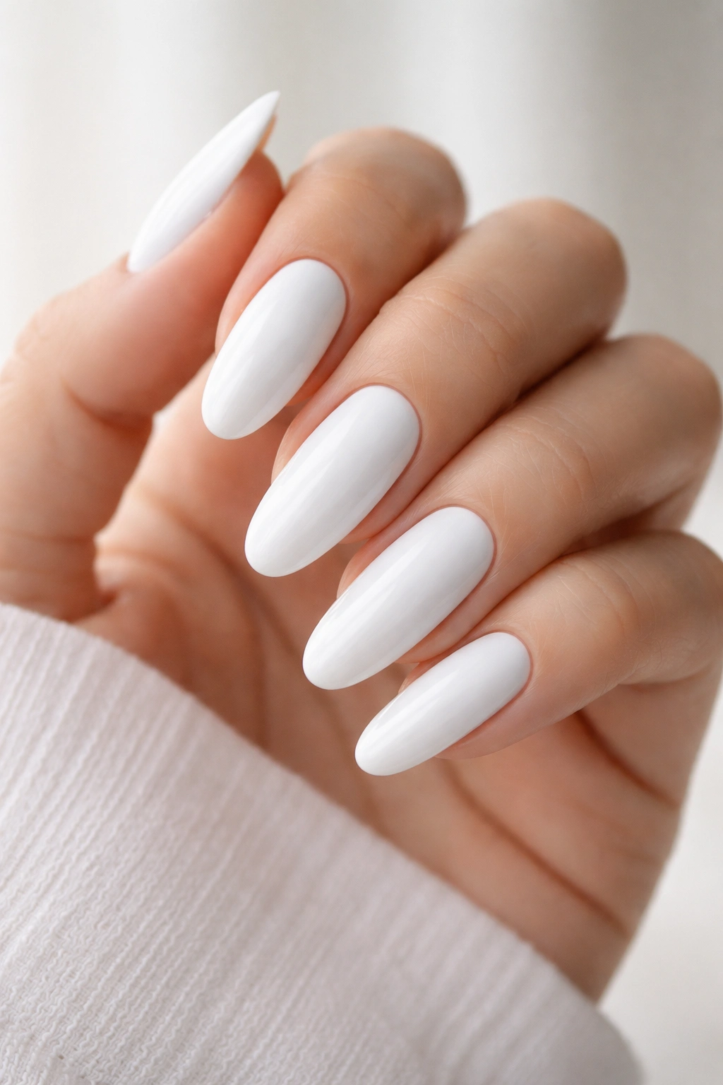 Close-up of long oval nails with pure glossy white polish