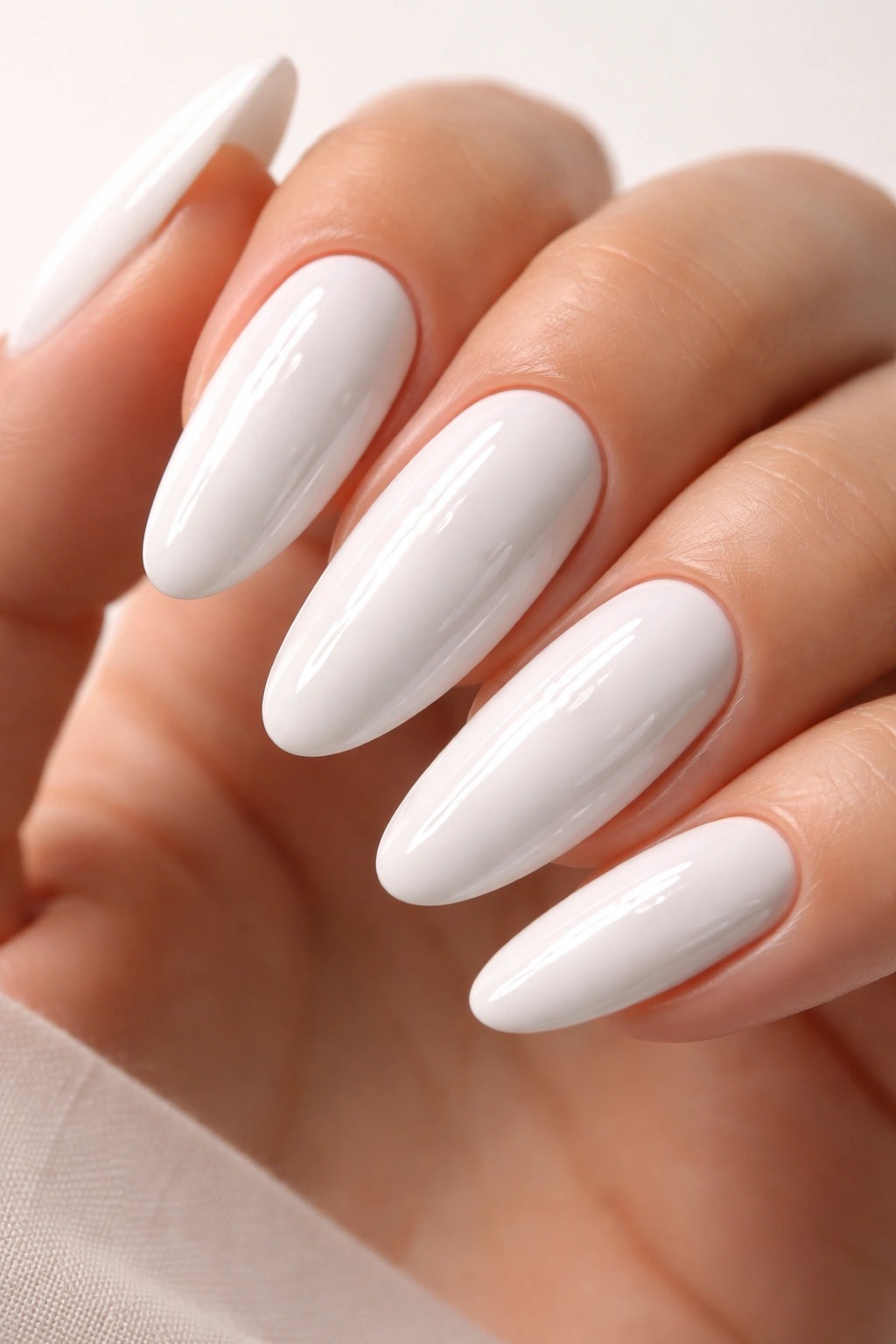 Close-up of long oval nails in glossy white with a glass-like shine