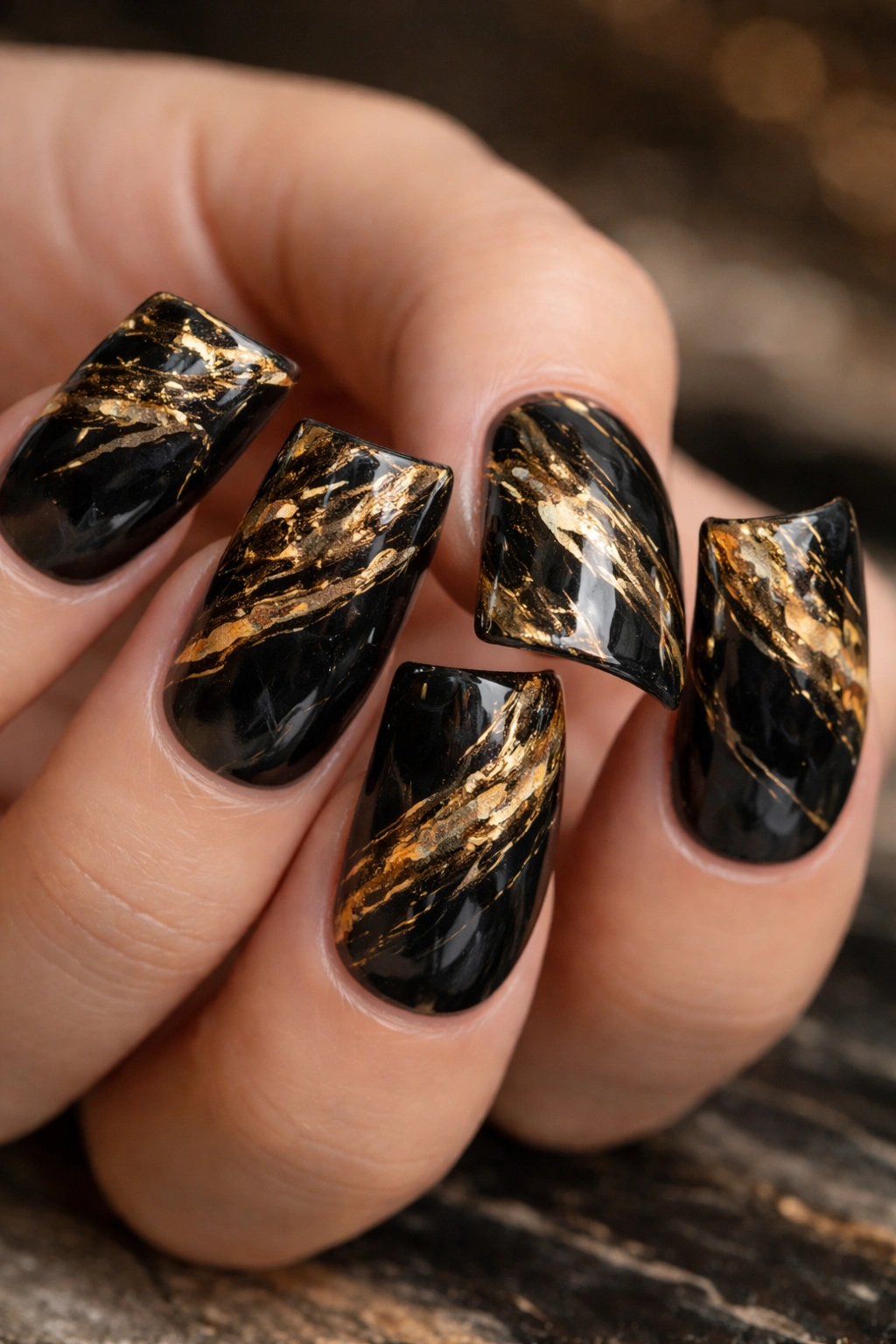 Close-up of gold and black marble duck nails with swirls