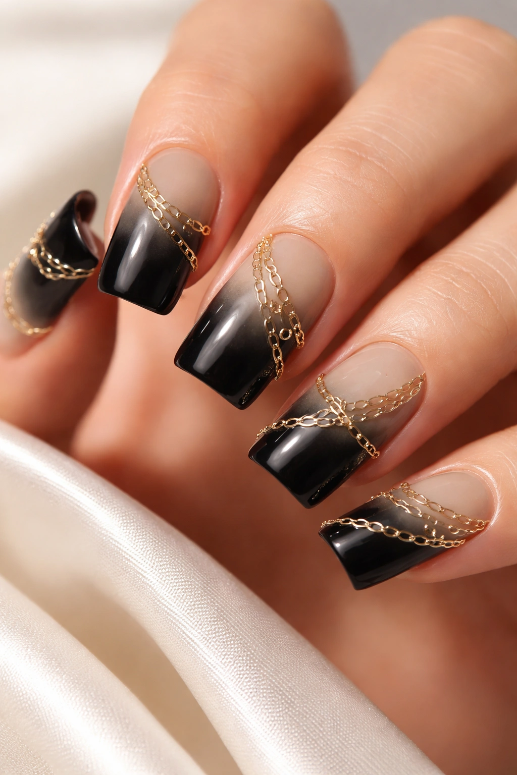 Close-up of black duck nails with gold chain links scattered across the gradient