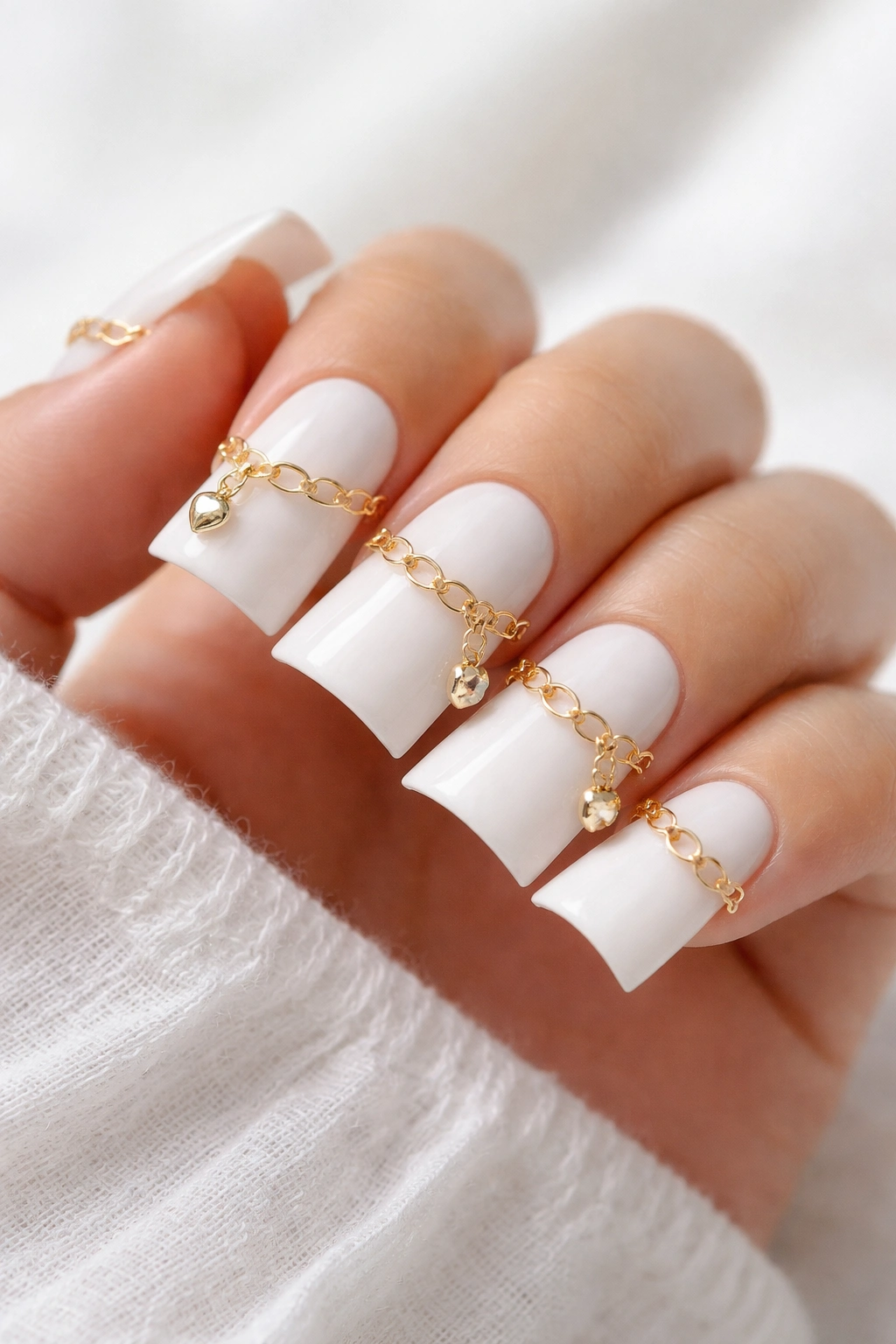 Close-up of Elegant Minimalist Gold Link Charm White Duck Nails with gold chains across the nail.