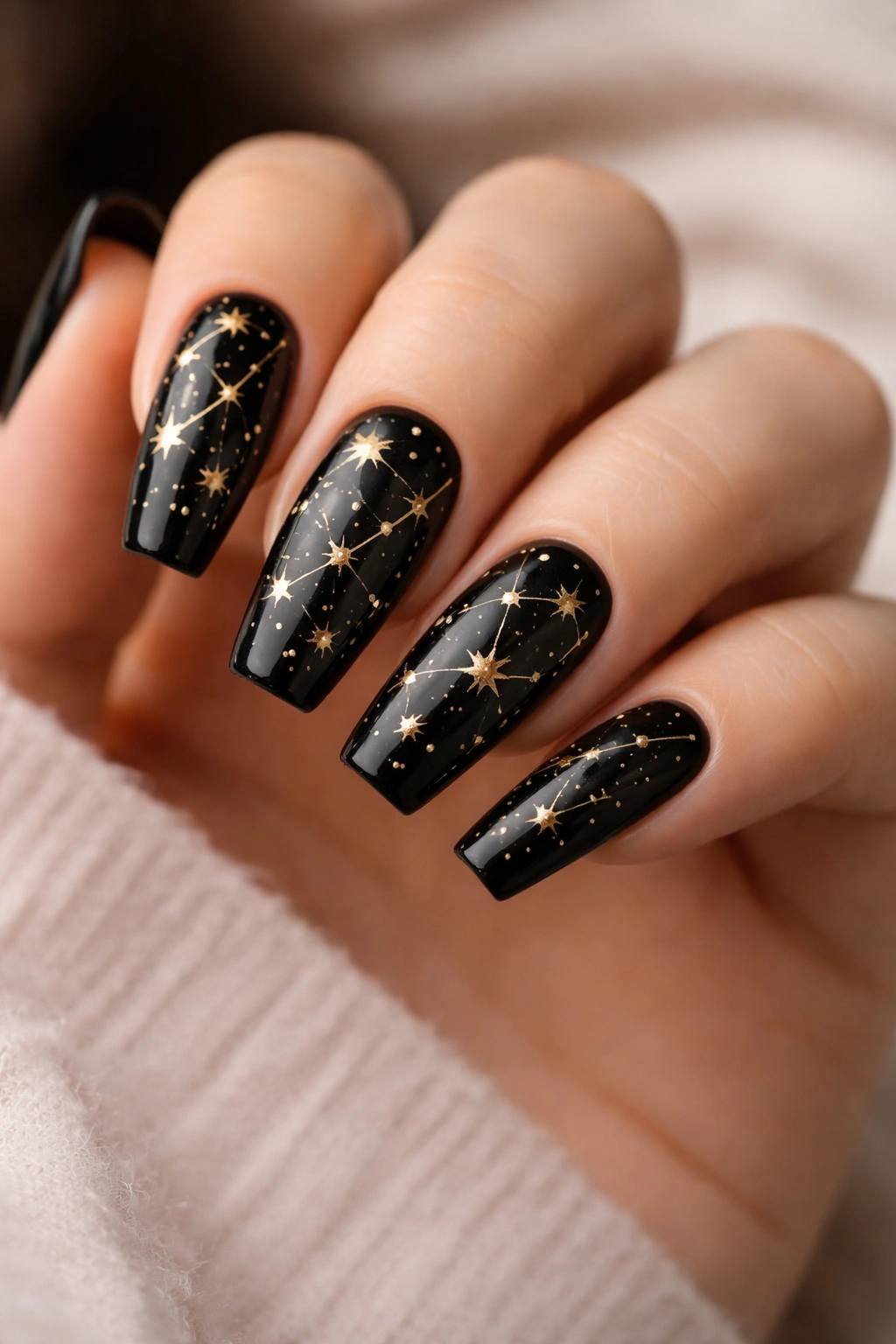 Close-up of black coffin nails with gold constellation stars and lines