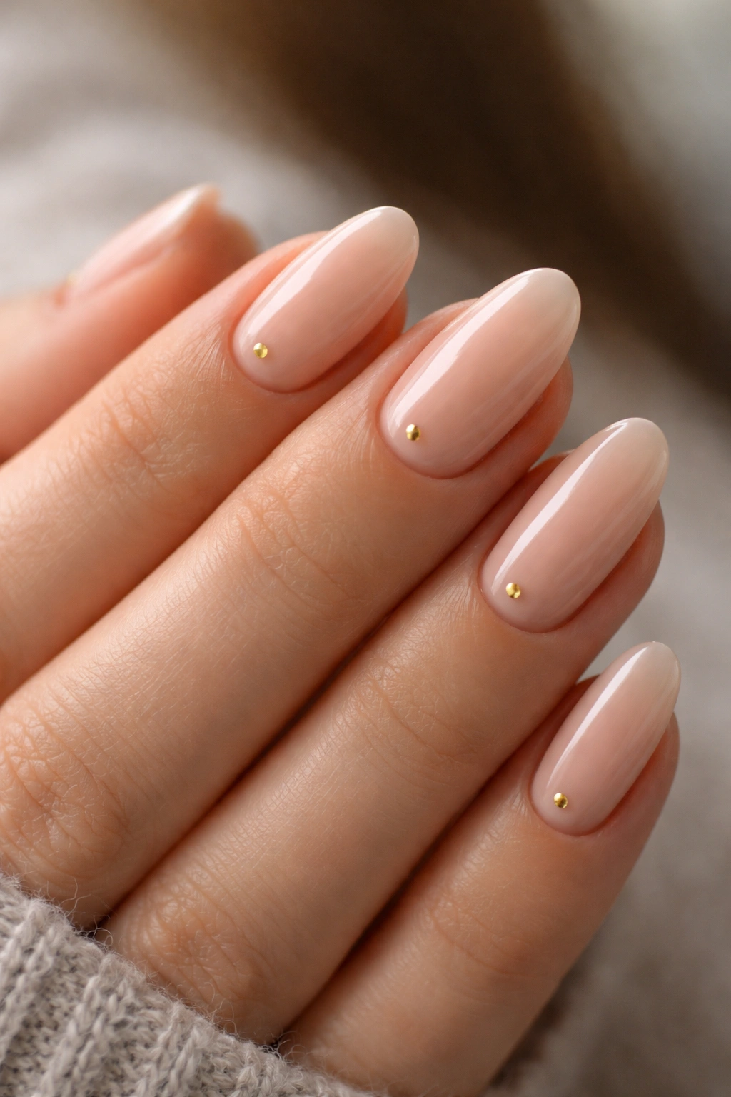 Short almond nails with tiny gold dots on a sheer glossy base