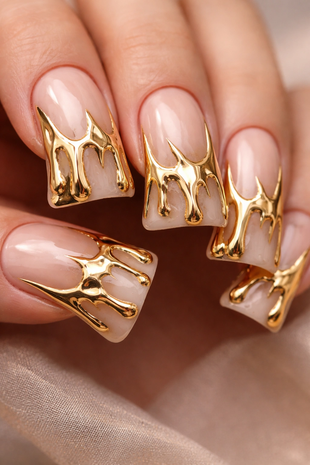 Close-up of gold drip duck nails with flowing metallic patterns