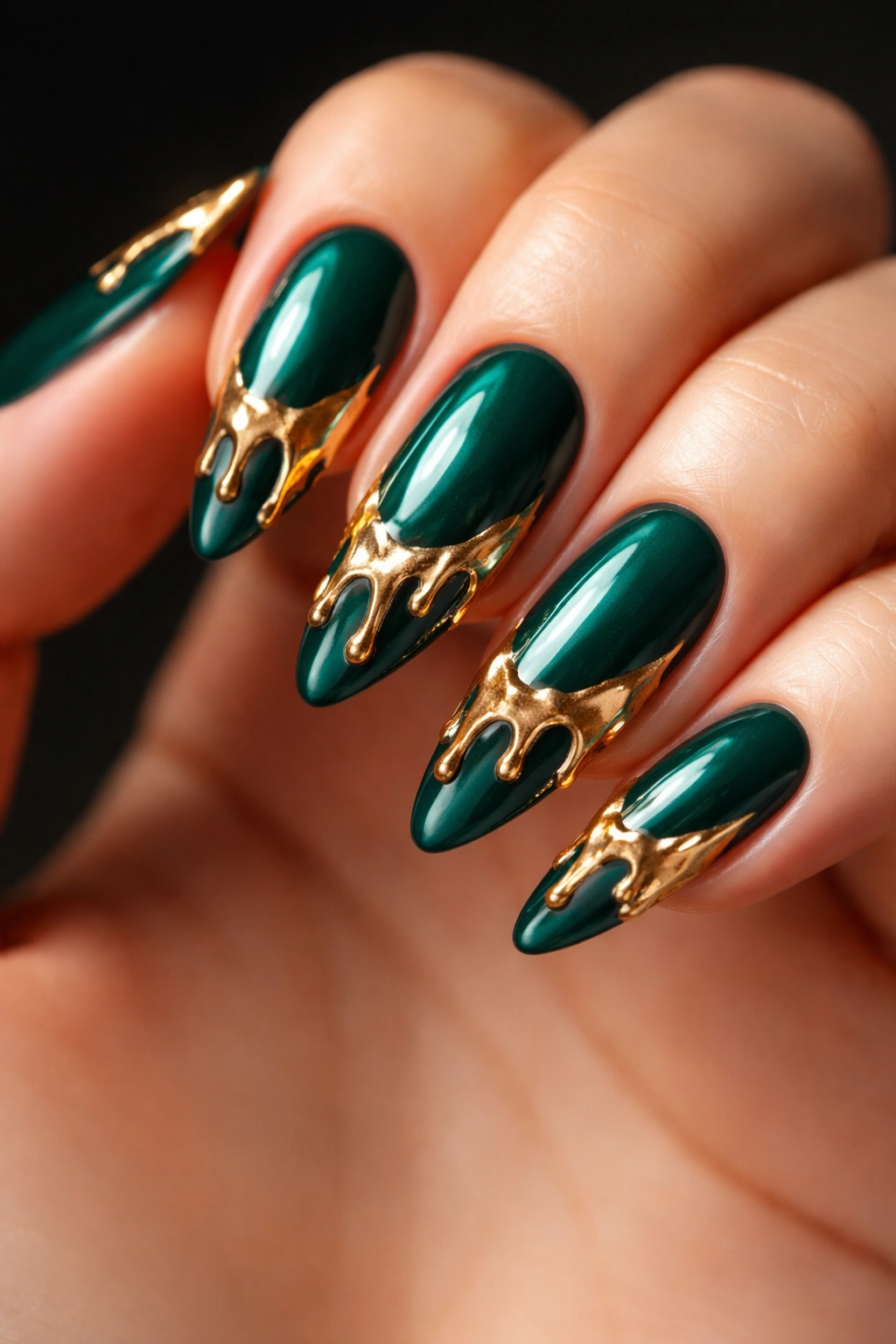 Close-up of emerald green nails with glossy molten gold drip art