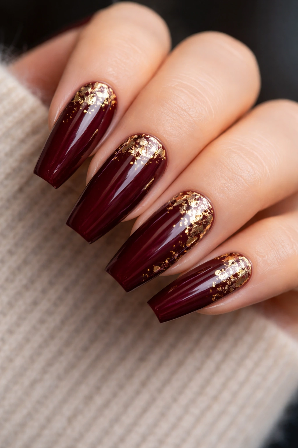 Dark red ballerina nails with gold flecks close-up