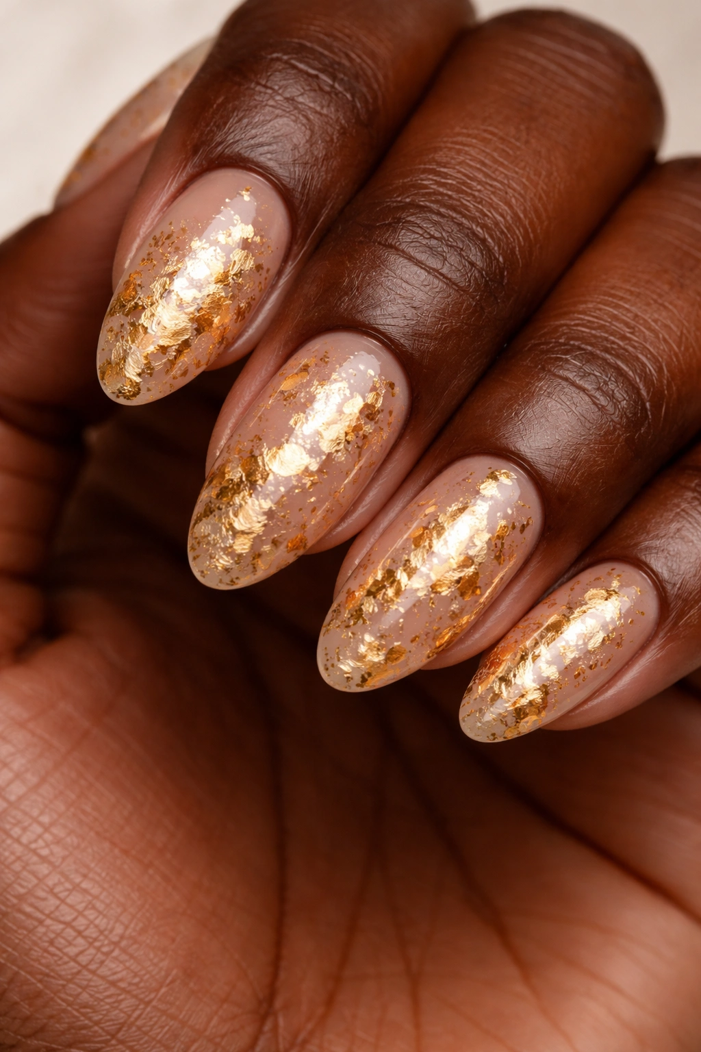 Dark-skinned hand with gold foil nail art