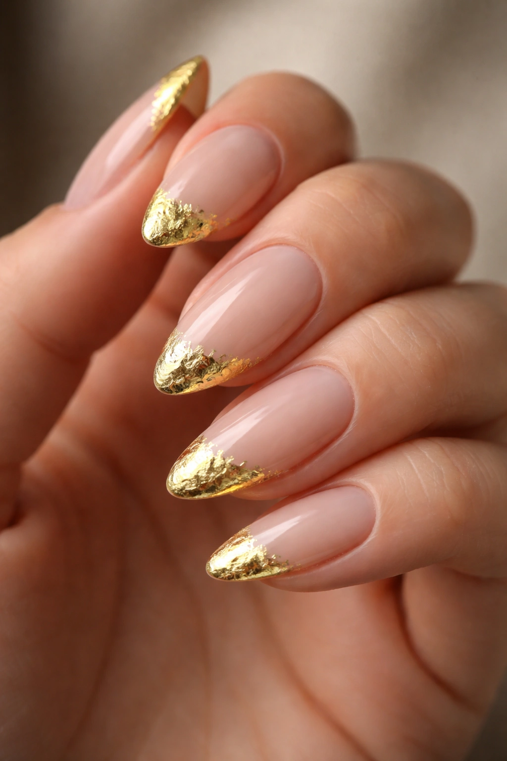 Almond nails with sheer nude base and scattered gold foil tips
