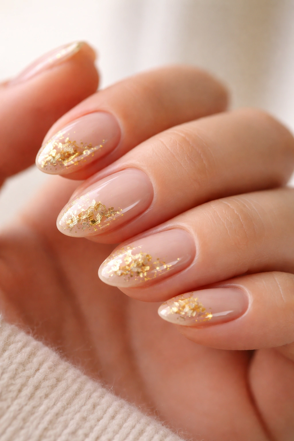 Short almond nails with sheer base and irregular gold foil accents