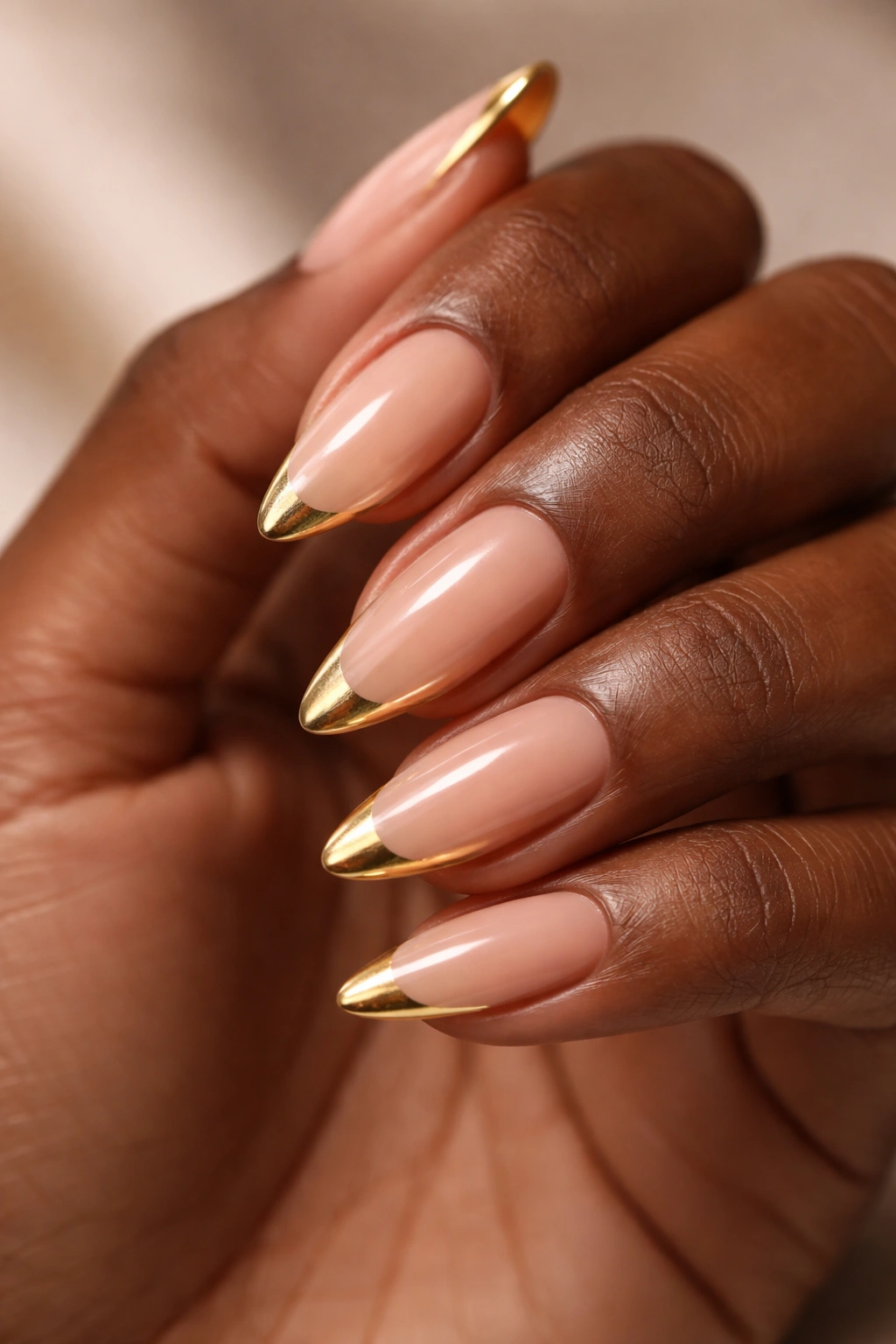 Dark-skinned hand with gold French tip nails