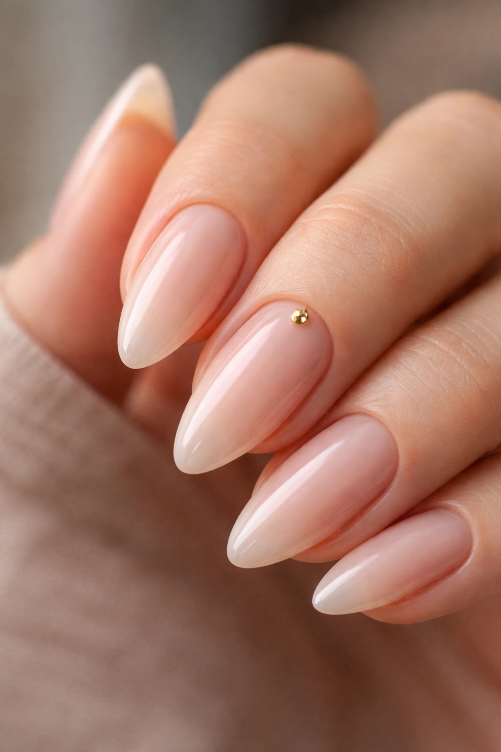 Almond nail with a single small gold gem near the cuticle