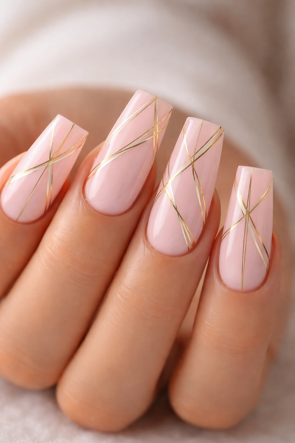 Nails with light pink base and thin gold geometric lines