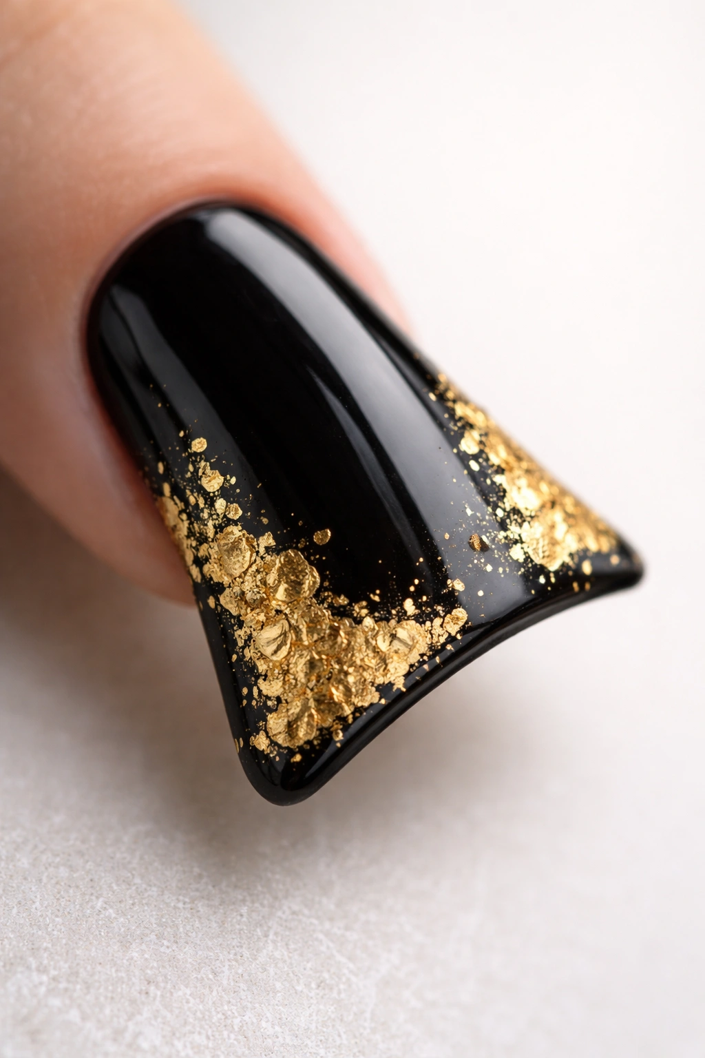 Close-up of a duck nail with black base and gold leaf accents along the curved edge