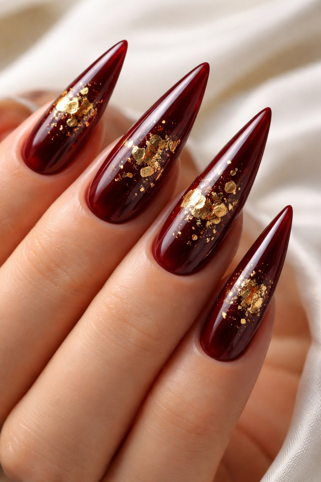 Dark red stiletto nails with encapsulated gold leaf inside gel