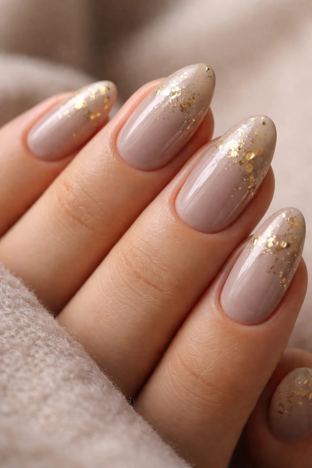 Taupe almond nails with scattered gold leaf fragments