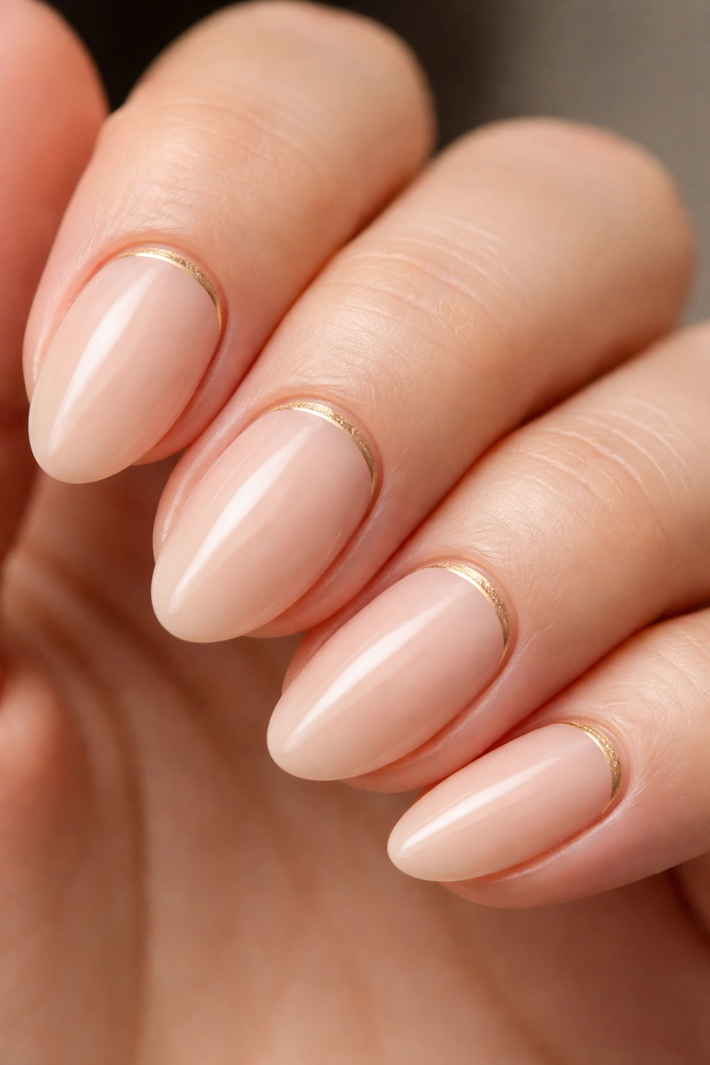 Close-up of a nude base almond nail with a fine gold line