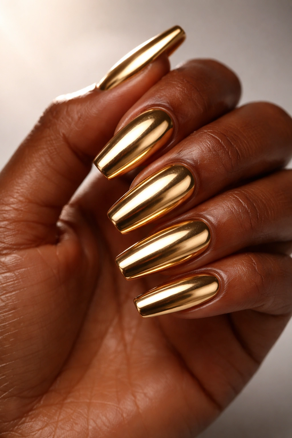 Close-up of dark-skinned hand with gold metallic nails