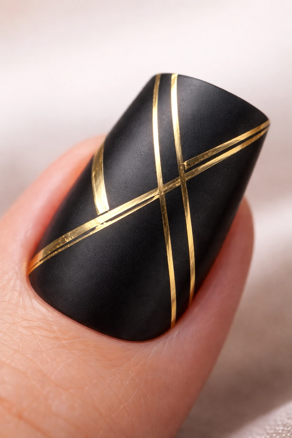 Close-up of a duck nail with black base and gold geometric stripes