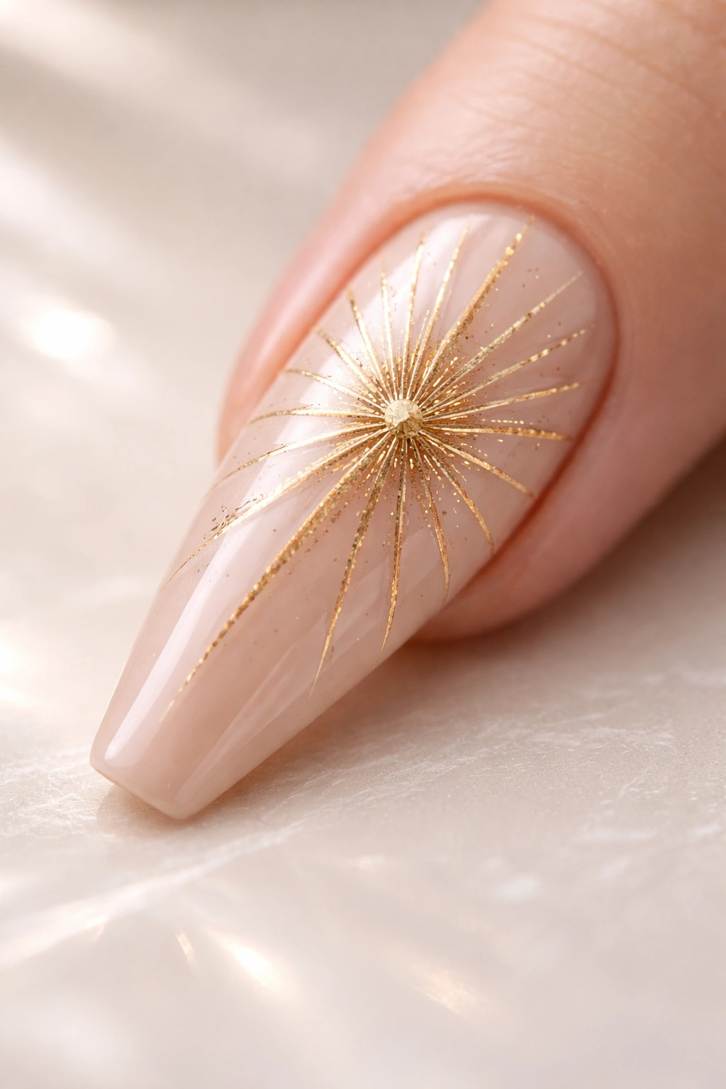 Close-up of a coffin nail with gold sunburst rays on a nude base