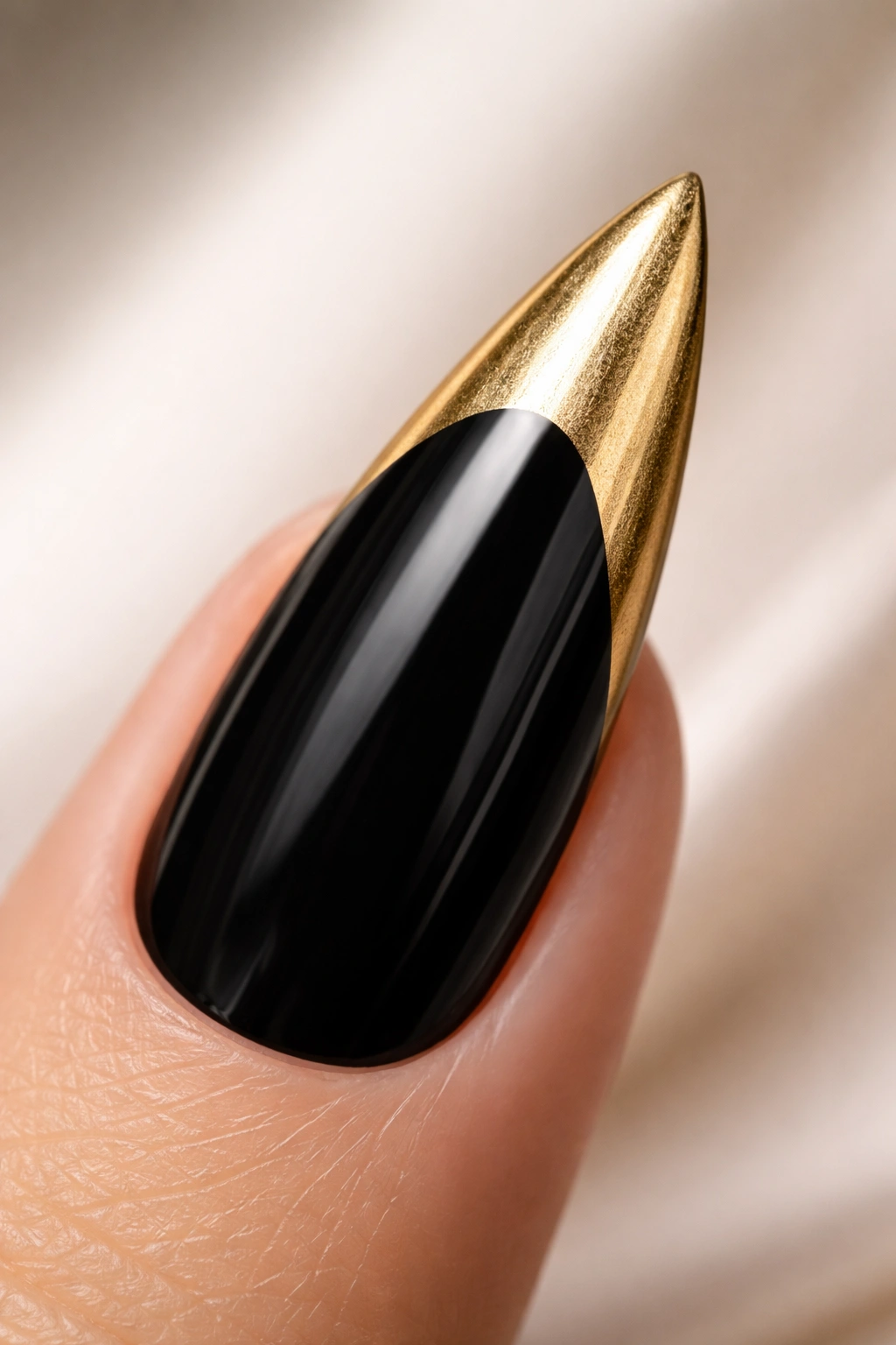 Stiletto nail with black base and gold metallic tip