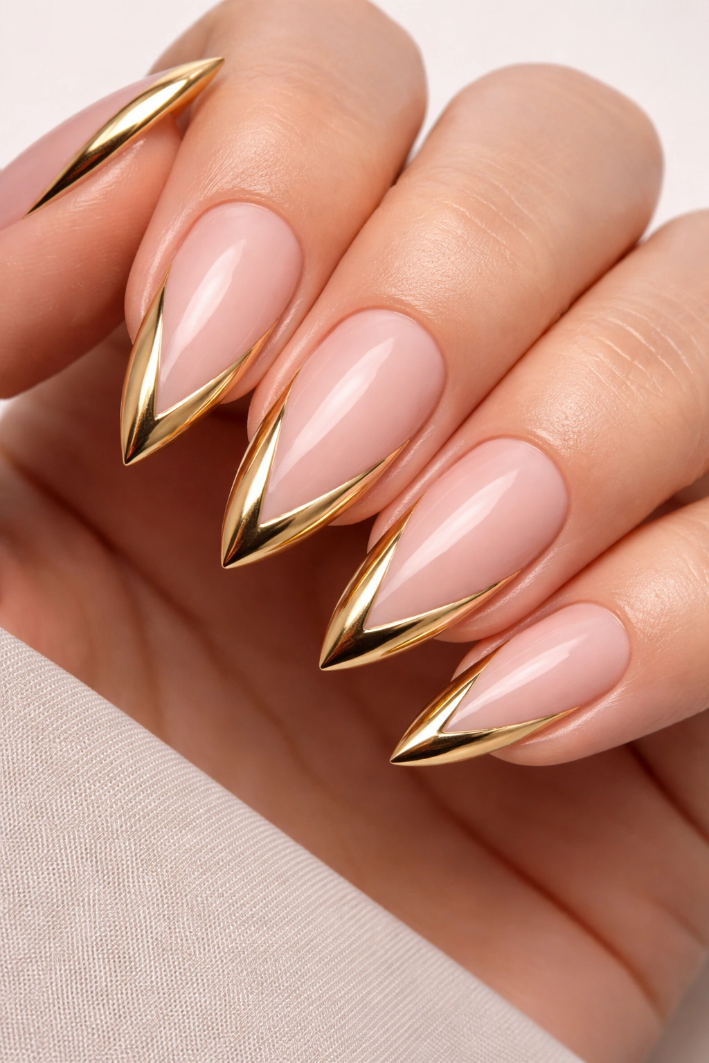 Nails with gold V-shaped French tips on almond nails