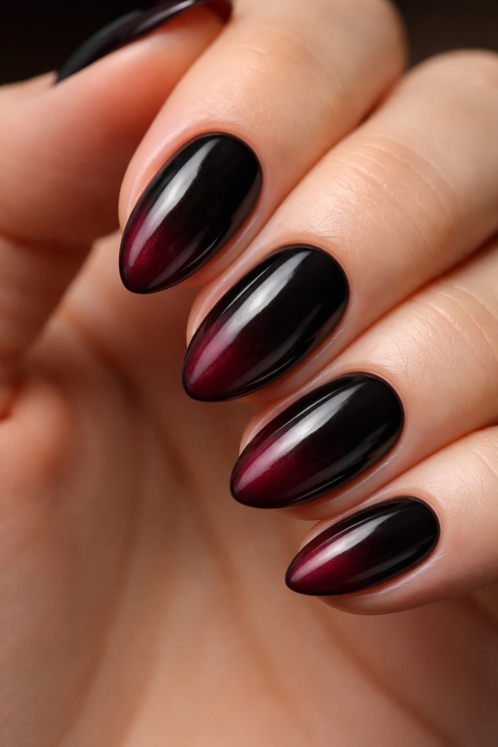 Close-up of a short almond nail with black-to-burgundy gothic ombré in a smoky fade