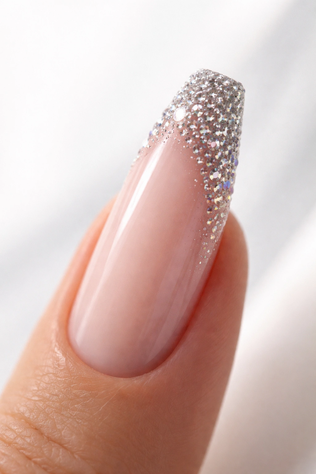 Close-up of coffin nail with rhinestone halo at tip on white background