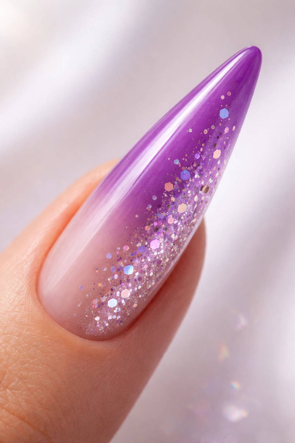 Close-up of gradient purple-to-clear stiletto nail with suspended confetti