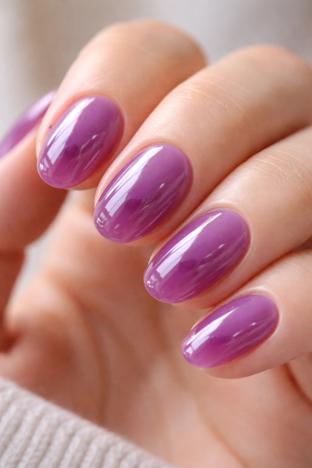 Close-up of a short oval nail with a translucent grape jelly purple finish