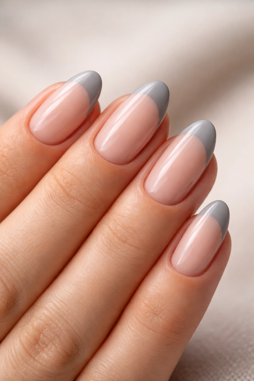 Close-up of short almond nails with gray tips on a sheer pink base.