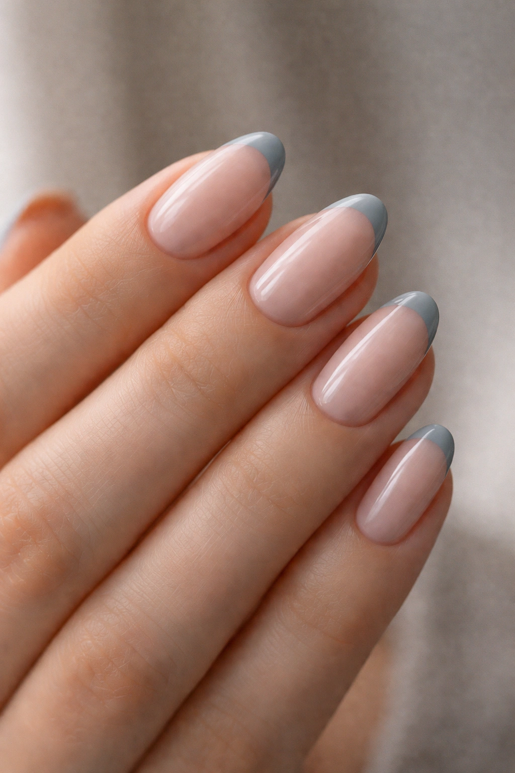 Close-up of short almond nails with sheer pink base and thin gray micro-French tips