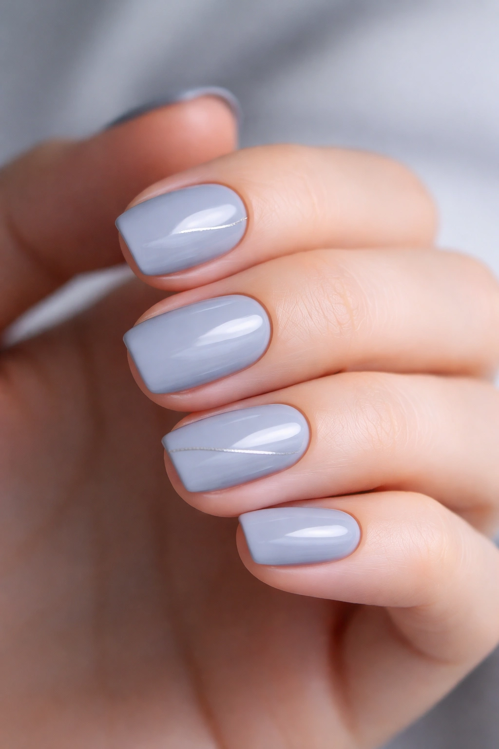 Close-up of nails in cool-toned gray with a single fine accent line on one nail