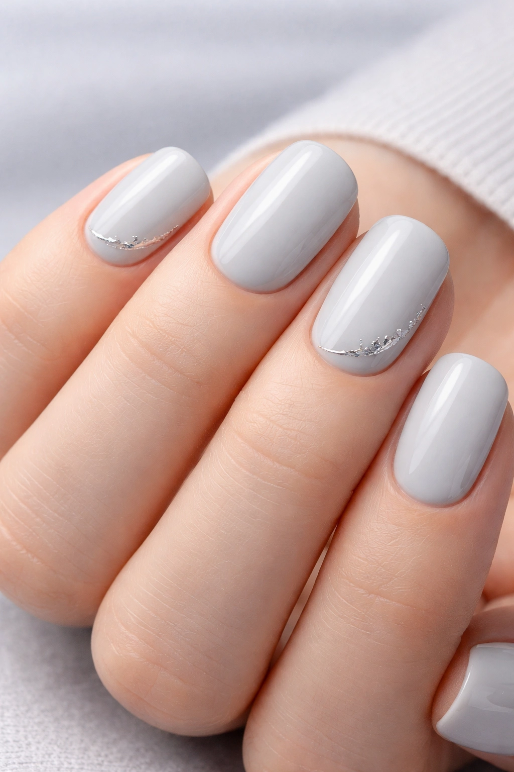 Close-up of light gray squoval nails with metallic silver details