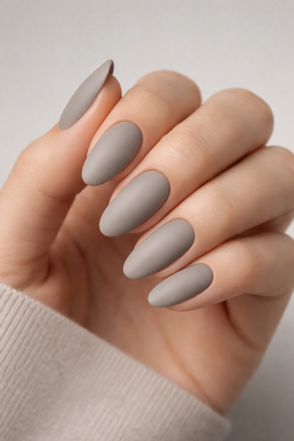 Close-up of oval nails in soft gray-taupe matte finish