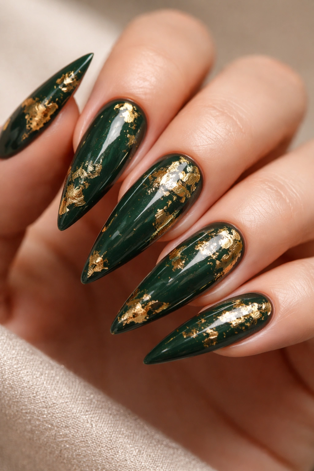 Stiletto nails with dark green base and gold leaf accents