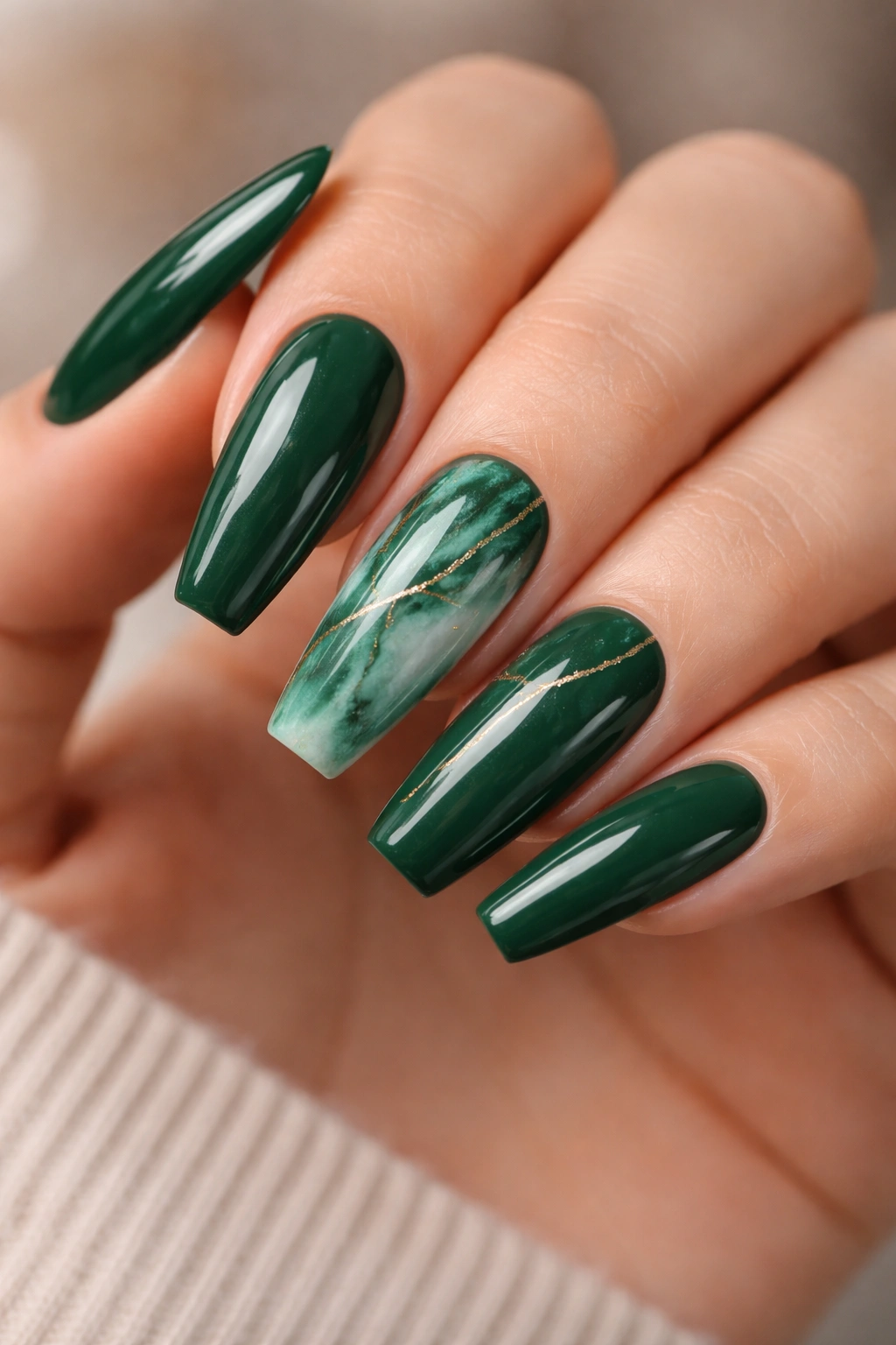 Emerald marble nails with fine gold lines on a hand