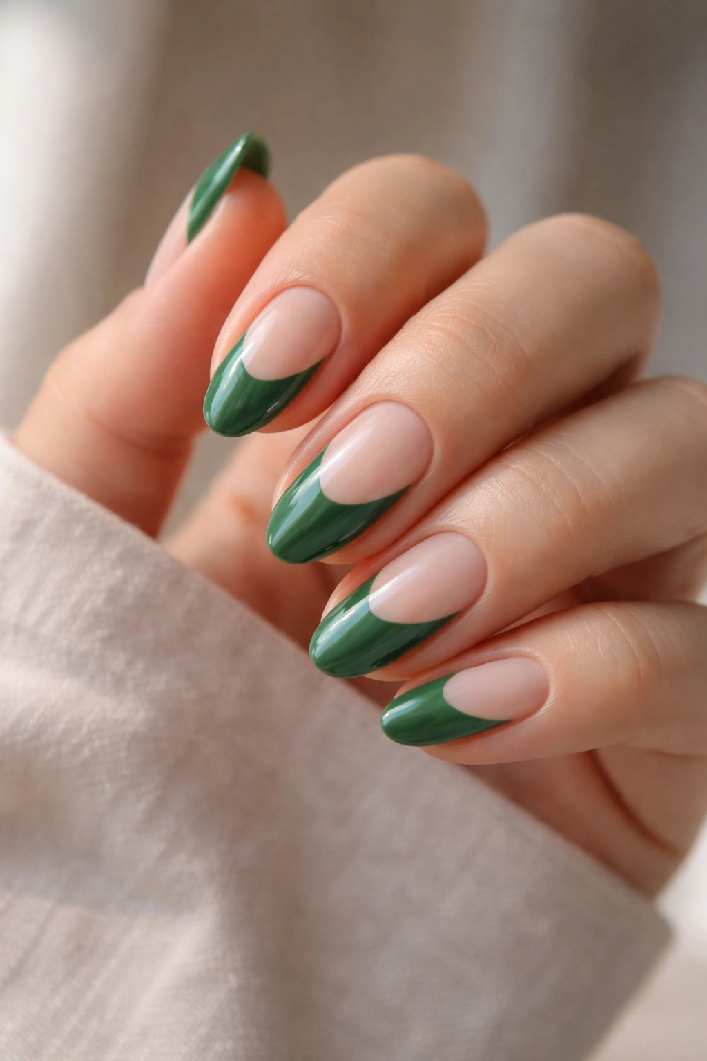 Close-up of short almond nails with green polish and negative-space design