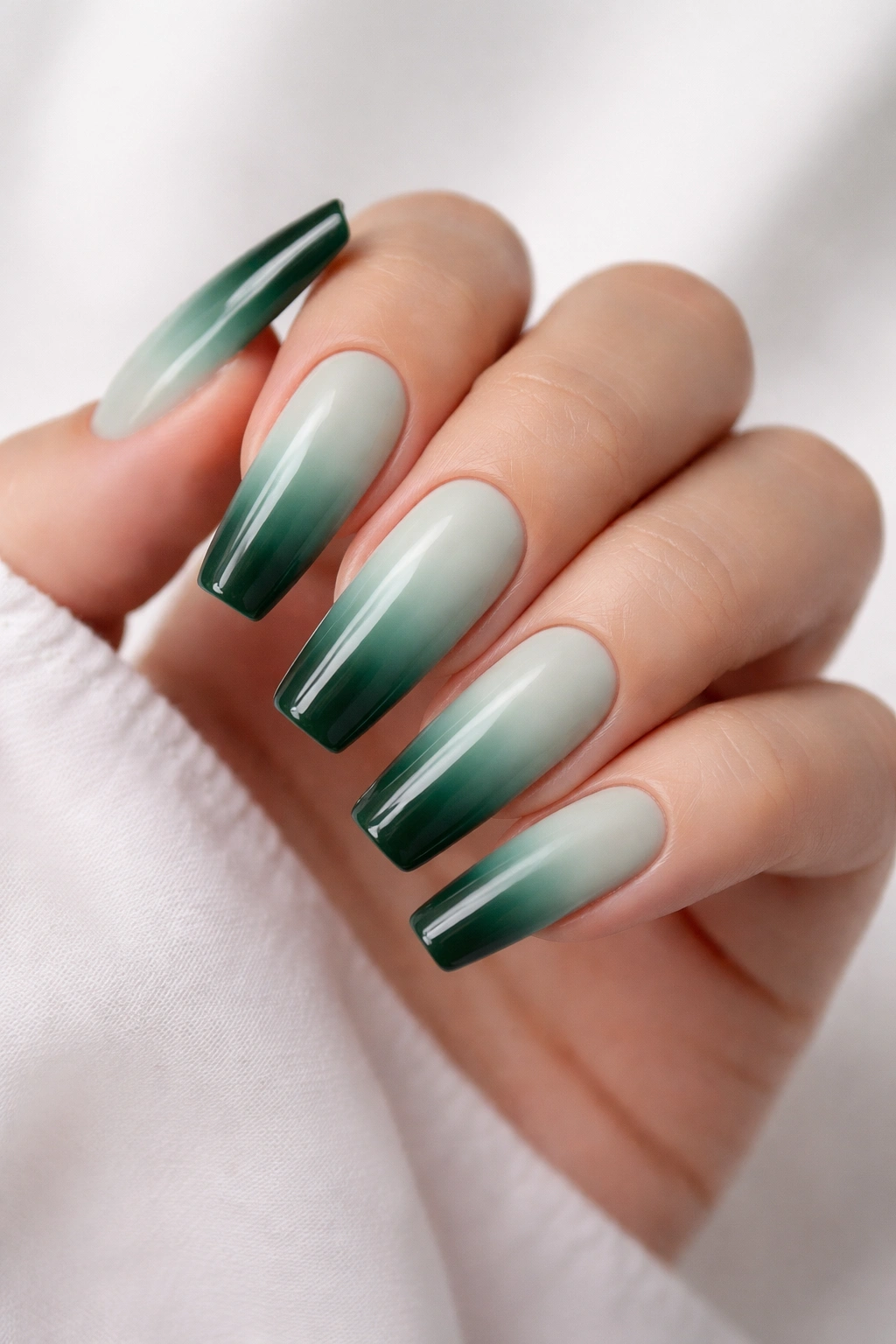 Close-up of coffin nails in mint-to-forest green ombre with glossy finish
