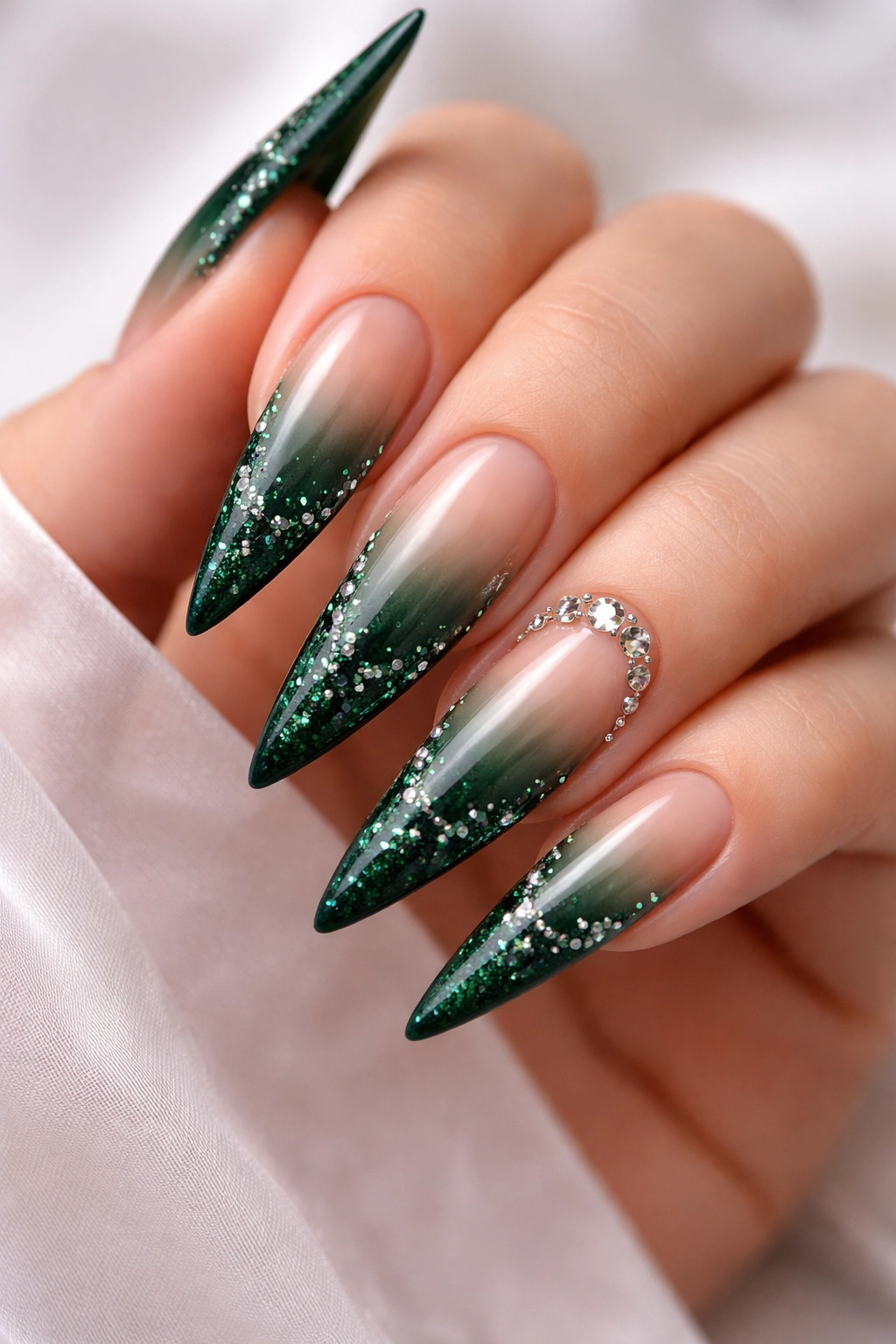 Dark green to nude ombre stiletto nails with glitter tips and rhinestones