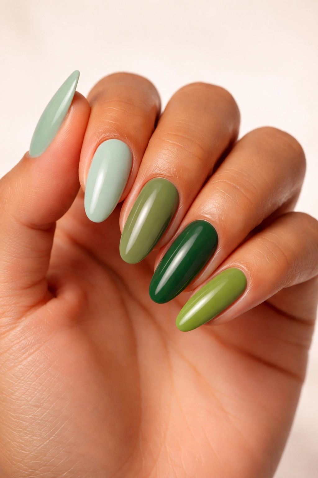 Hand with nails in mint, olive, and emerald greens to show skin-tone shade options.