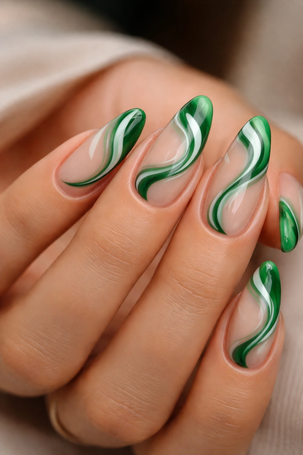 Almond nails with green swirls on nude base.