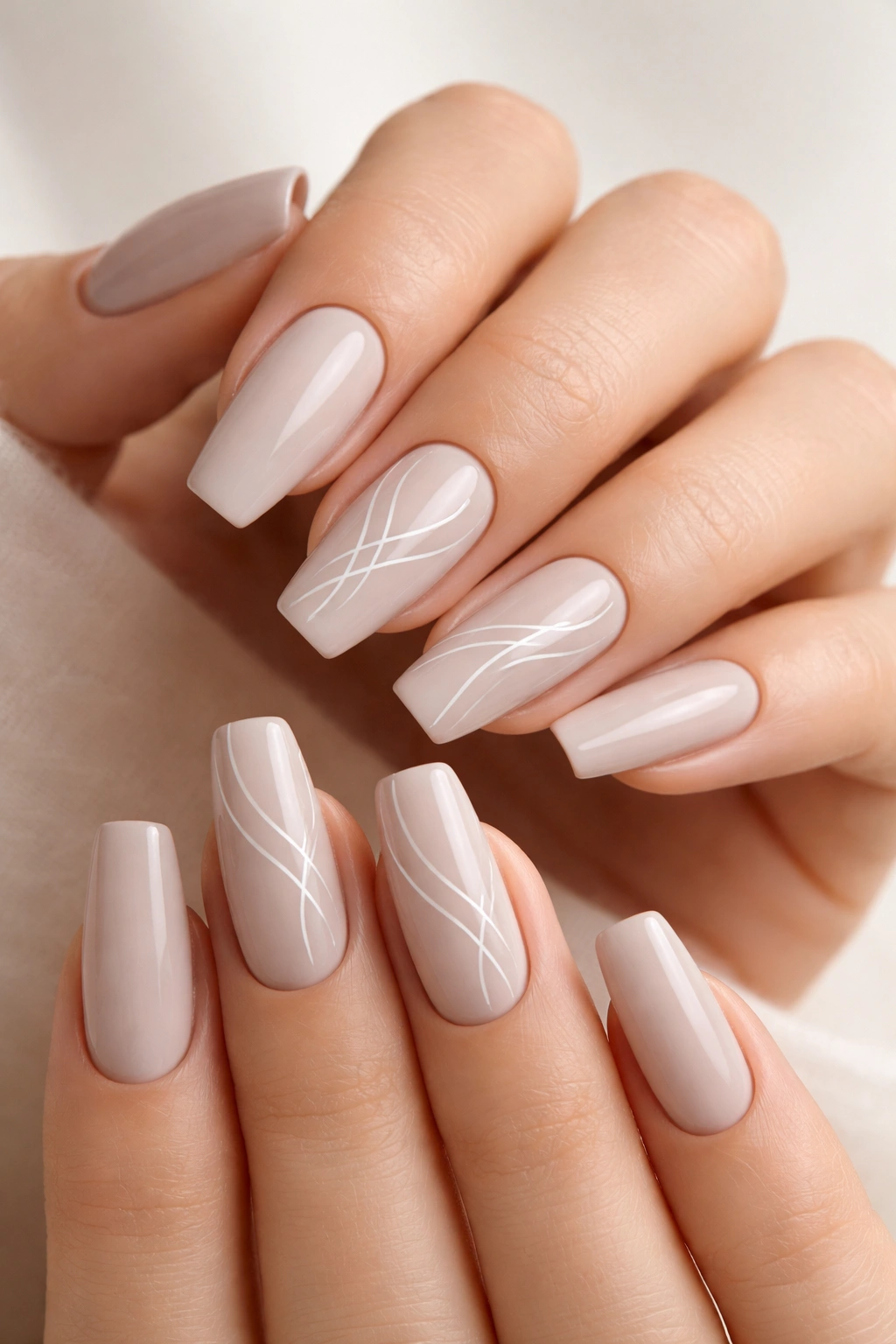 Close-up of nails with soft greige base and fine white line art on accent nails