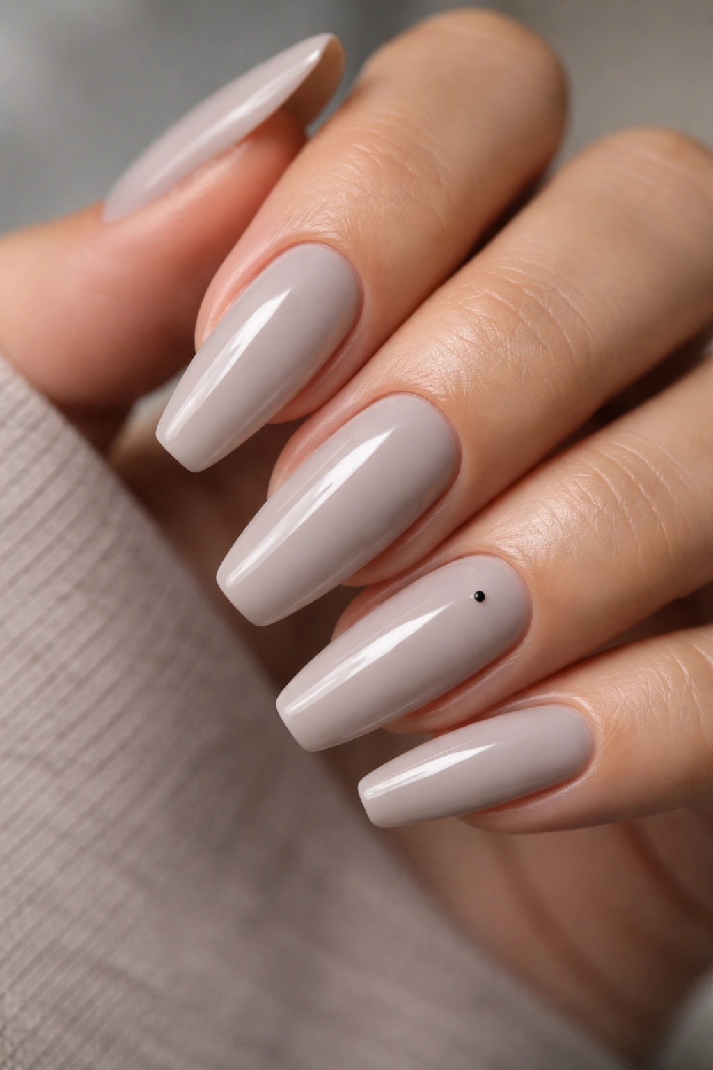 Greige ballerina nails with a tiny dot accent on one accent nail